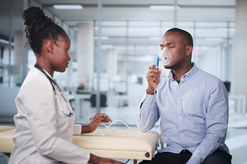 Doctor assisting a patient with COPD (a chronic condition) with learning how to use his CPAP machine.